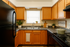 Charming kitchen with warm wooden cabinets, sleek black appliances, and bright natural light pouring through a window above the sink.