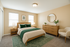 Elegant bedroom with plush bedding, wooden furniture, and modern decor features soft beige walls, creating a cozy and inviting atmosphere.