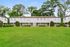 Charming two-story apartment complex with lush green lawns, surrounded by mature trees and vibrant shrubs, offering a welcoming and serene community atmosphere.