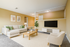 Bright and inviting living room with modern decor, featuring a cozy beige sofa, stylish coffee table, and mounted TV, perfect for relaxation and entertainment.