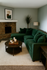 Cozy living room featuring a plush green sectional sofa, rustic stone fireplace, and elegant decor with modern artwork.