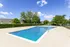 Inviting outdoor pool surrounded by lush greenery and clear blue skies, perfect for relaxation and leisure.