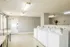 Well-lit laundry room with modern white washing machines and stylish gray walls, offering a clean and efficient space for laundry tasks.