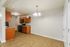 Modern kitchen with elegant wooden cabinetry, granite countertops, and a bright dining area with stylish lighting.