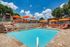 Expansive pool with sundeck, lounge chairs, and orange umbrellas