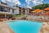 Expansive dual pool feature, exterior of apartments, orange umbrellas and chairs