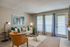 Carpeted living space with large windows and class patio door, couch, wall art, orange chair and table