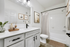 Bathroom with quartz counters, large mirror, vanity lighting, and white cabinetry