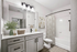 Bathroom with quartz counters, large mirror, vanity lighting,