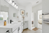 Bathroom with quartz counters, large mirror, vanity lighting, and white cabinetry