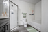 Bathroom with quartz counters, large mirror, vanity lighting, and white cabinetry