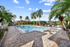 expansive pool and sundeck surrounded by trees with an orange cabana area