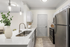 Vinyl floors, stainless-steel appliances, white quartz countertop, and pendant lighting.