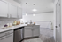 Vinyl floors, stainless-steel appliances, white quartz countertop, and pendant lighting.
