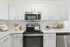 Vinyl floors, stainless-steel appliances, white quartz countertop, and pendant lighting.