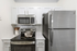 Vinyl floors, stainless-steel appliances, white quartz countertop, and pendant lighting.