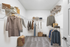 Carpeted walk in closet with clothes