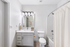 Bathroom with quartz counters, large mirror, vanity lighting, and white cabinetry