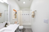 Bathroom with quartz counters, large mirror, vanity lighting, and white cabinetry