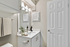 Bathroom with white counters, large mirror, vanity lighting, and white cabinetry.