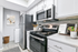 Modern kitchen featuring vinyl flooring, stainless-steel appliances, and a white quartz countertop