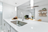 Kitchen bar with white quartz counters, undermount sink, gooseneck faucet, and pendant lighting.