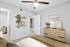 Carpeted bedroom with ceiling fan, beige bedding, dresser, and wall shelves