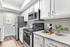 Modern kitchen featuring vinyl flooring, stainless-steel appliances, and a white quartz countertop