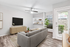 Vinyl floor living space with rug, grey couch, TV, ceiling fan, large windows, and built-in bookshelf.