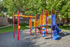 Colorful playground with climbing feature, slide, and monkey bars.