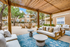 Poolside cabana with couch, tables, and rug.