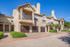 Exterior of two-story apartment with garage, driveway, sidewalk, and bushes.