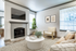 Living room with carpet, fireplace, flat-screen TV, beige chair, round coffee table, and plant