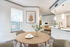 Dining area with three windows, wooden circular table, and four chairs.