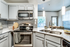 Modern kitchen with white quartz counters, stainless steel appliances and modern pendant lighting.