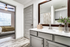 Bathroom with gray door and cabinets, large vanity mirror, and white counters.