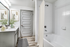 Bathroom with wood vinyl floor, white countertop, and bathtub with curtains.