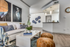 Living room with two orange ottomans, white table, white couch and wall art, pendant lighting and bar