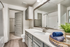 Bathroom with gray door and cabinetry, large vanity mirror, and white counters. door to large walk in closet
