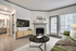 Living room with black round table, wooden entertainment area, flat-screen TV, wood vinyl floor, and beige rug.