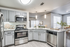 Modern kitchen with white quartz counters, stainless steel appliances and modern pendant lighting.
