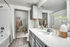 Bathroom with gray door and cabinetry, large vanity mirror, and white counters. door to large walk in closet