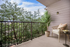 Balcony with potted plant, metal railing, and beige lounge furniture