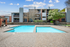 Dual pool feature with apartment exterior in back ground