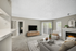Gray couch, carpet and beige rug, wooden shelf and flat TV