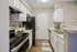Kitchen with stainless steel appliances, white cabinetry, wood flooring