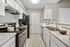 Kitchen with stainless steel appliances, white cabinetry, wood flooring