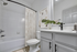 Bathroom with quartz counters, large mirror, vanity lighting, and white cabinetry