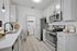 Kitchen with vinyl floors, stainless-steel appliances, white quartz countertop, and pendant lighting