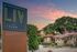 Wooden monument sign with exterior of community, trees, and a sunset